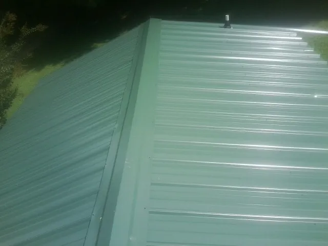 New green metal panels meeting at the ridge of a roof — Flat Roof Repair work by our crew in Blowing Rock