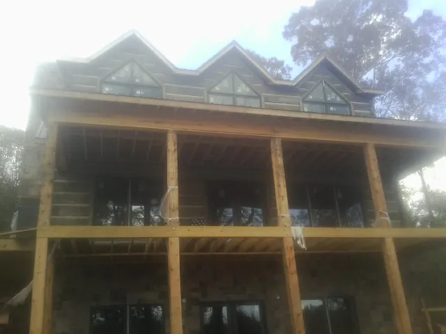 Dormers and porch framing on a large log home under construction — Roof Coating work by our crew in Blowing Rock