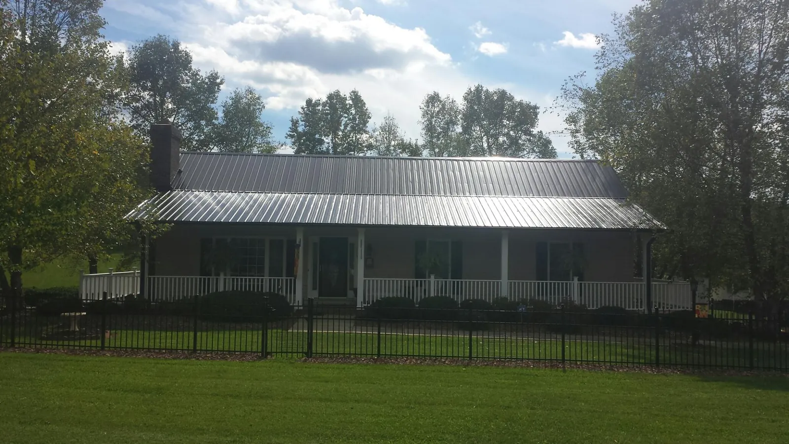 Gray metal roof on a brick ranch with a full width front porch — Gutter Guard Installation work by our crew in Blowing Rock