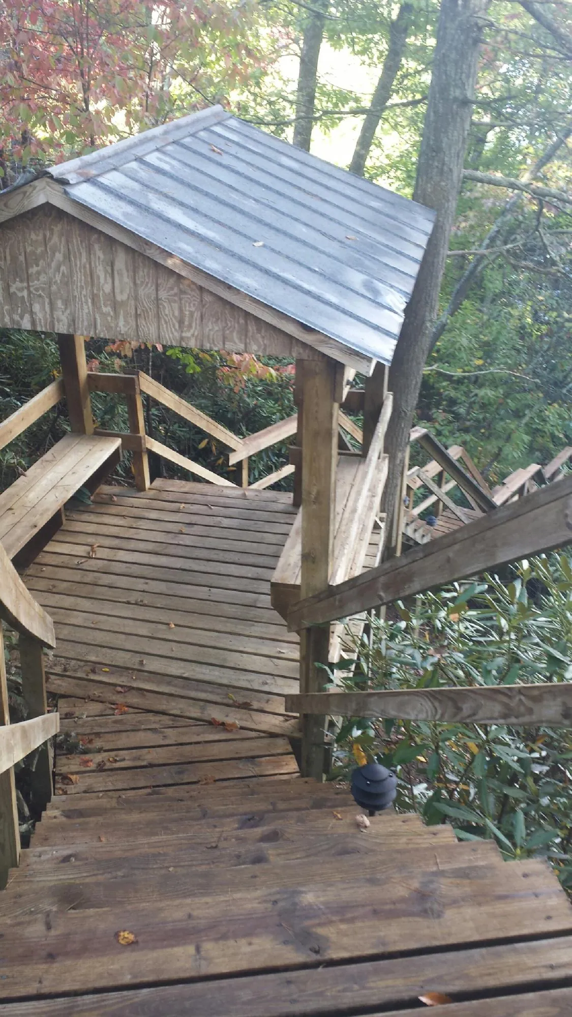 Metal roofed shelter over wooden steps on a wooded walkway — Skylight Repair & Installation work by our crew in Blowing Rock
